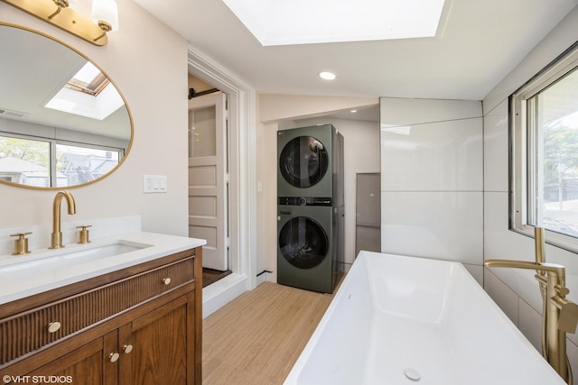 605 Home Ave, Oak Park, IL 60304 - bathroom with stacked washer and clothes dryer, wood finished floors, recessed lighting, healthy amount of natural light, and a bathtub