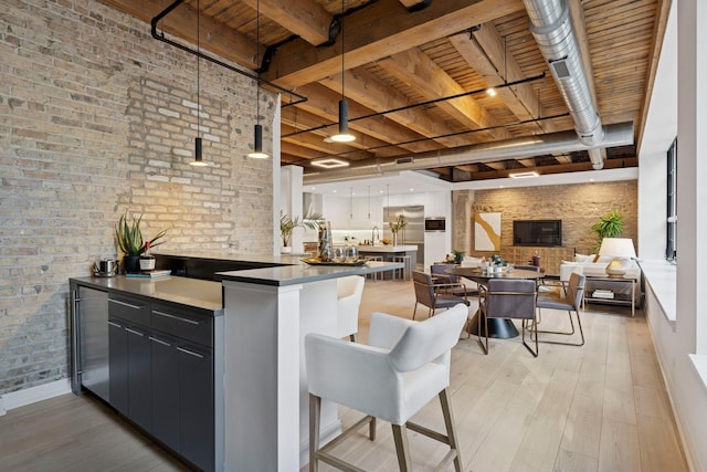 223 W Lake St Unit 3N, Chicago, IL 60606 - kitchen with light wood finished floors, wood ceiling, brick wall, beam ceiling, and a kitchen breakfast bar