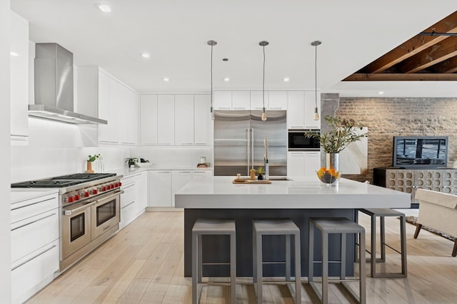 223 W Lake St Unit 3N, Chicago, IL 60606 - kitchen with built in appliances, wall chimney exhaust hood, light wood-style flooring, a kitchen breakfast bar, and light countertops