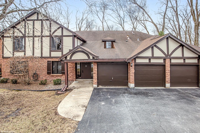 8245 Willow Dr Unit 43D, Palos Hills, IL 60465 - tudor home featuring driveway, an attached garage, roof with shingles, brick siding, and stucco siding