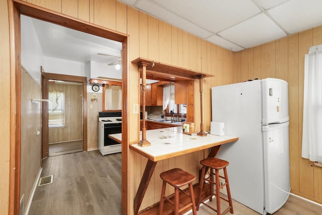 3132 Oak Park Ave, Berwyn, IL 60402 - kitchen with white appliances, tile countertops, wood walls, light wood-type flooring, and a drop ceiling