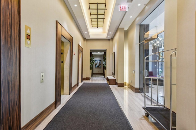 corridor featuring healthy amount of natural light, baseboards, elevator, and recessed lighting