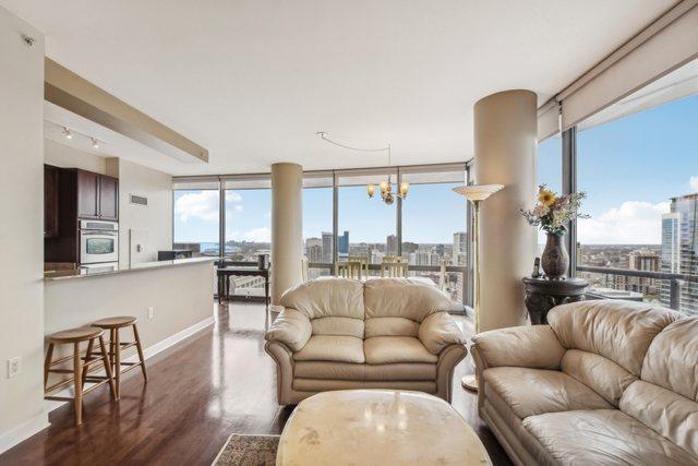 living room featuring dark wood-style flooring, a city view, baseboards, floor to ceiling windows, and a chandelier