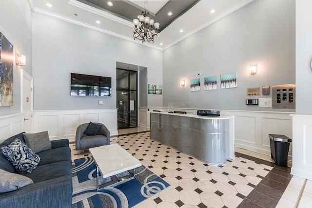 reception area featuring a high ceiling, crown molding, a decorative wall, recessed lighting, and a chandelier