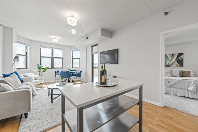 living room with an office area, light wood finished floors, and baseboards