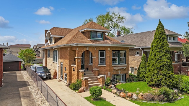 view of front of house featuring brick siding, roof with shingles, and an outdoor structure