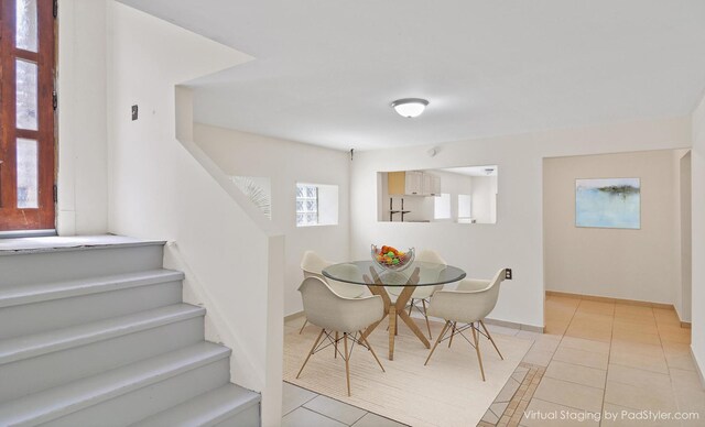 dining area featuring light tile patterned floors, stairway, and baseboards
