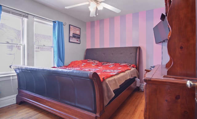 bedroom with wallpapered walls, wood finished floors, and a ceiling fan