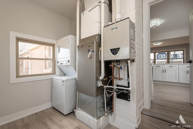 10925 Lyman Ave, Chicago Ridge, IL 60415 - laundry area featuring stacked washer and clothes dryer, light wood finished floors, tankless water heater, and baseboards