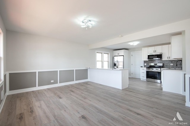 10925 Lyman Ave, Chicago Ridge, IL 60415 - kitchen featuring appliances with stainless steel finishes, light wood-type flooring, decorative backsplash, white cabinetry, and a peninsula