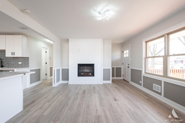 10925 Lyman Ave, Chicago Ridge, IL 60415 - unfurnished living room featuring light wood-style flooring, a large fireplace, and baseboards