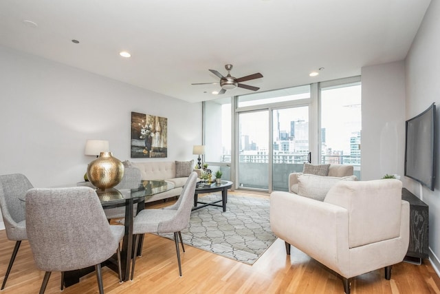 living room with light wood-type flooring, a ceiling fan, floor to ceiling windows, and recessed lighting