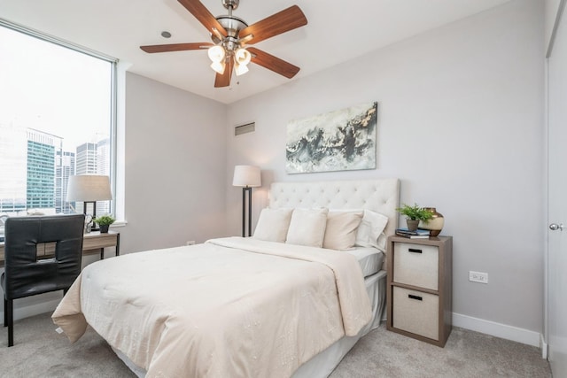 bedroom with light colored carpet, baseboards, a ceiling fan, and a view of city