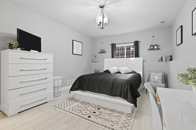 bedroom with light wood-style floors and a chandelier