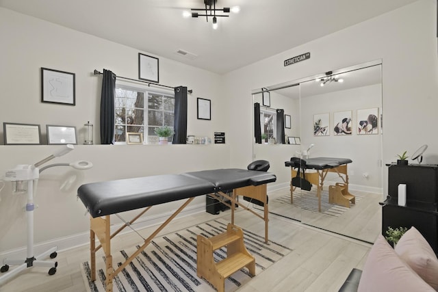 game room featuring baseboards, wood finished floors, and a chandelier