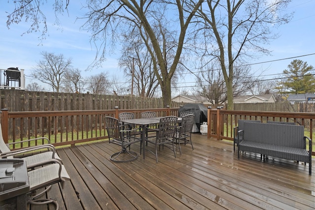 wooden deck with outdoor dining space and a fenced backyard