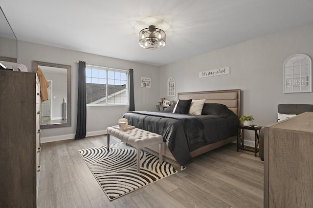 bedroom with wood finished floors, a chandelier, and baseboards