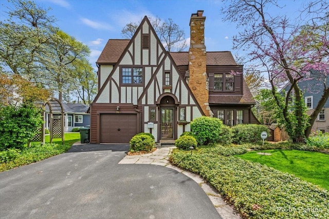 705 Hunter Rd, Glenview, IL 60025 - tudor house with a chimney, roof with shingles, a garage, driveway, and stucco siding