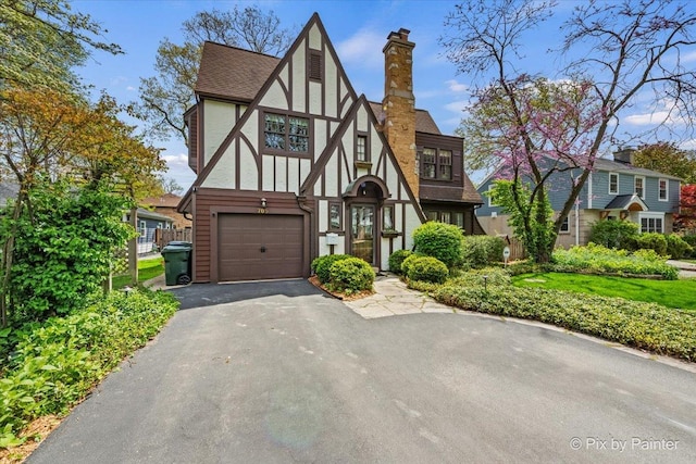 705 Hunter Rd, Glenview, IL 60025 - tudor house featuring an attached garage, stucco siding, a chimney, asphalt driveway, and a shingled roof