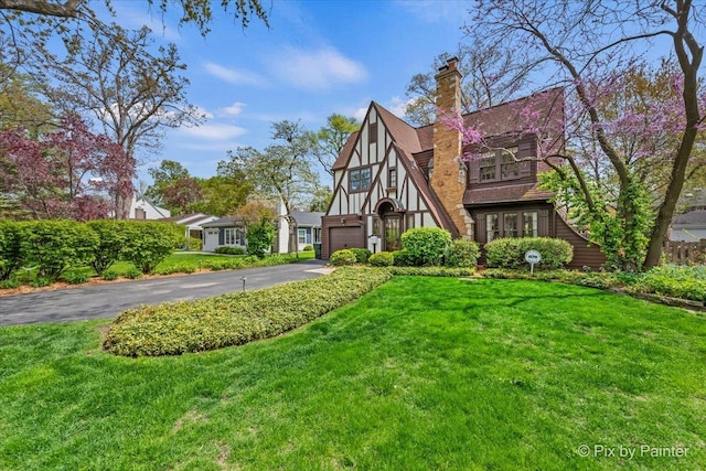 705 Hunter Rd, Glenview, IL 60025 - tudor house featuring asphalt driveway, a front yard, and a chimney