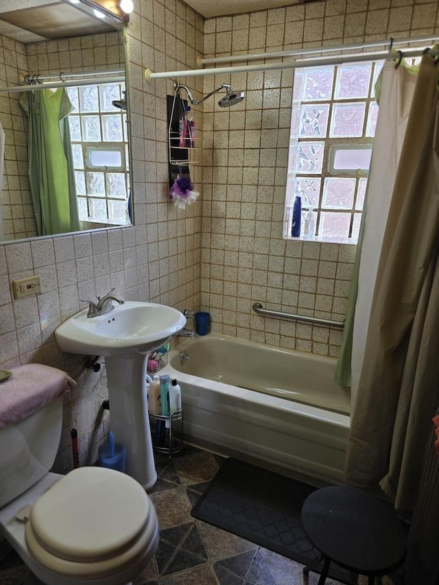 full bath with tile walls, toilet, plenty of natural light, shower / tub combo with curtain, and tile patterned floors
