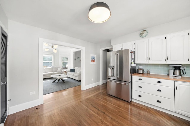 kitchen featuring high end refrigerator, baseboards, wood finished floors, white cabinetry, and tasteful backsplash