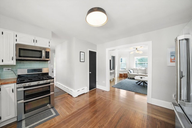 kitchen featuring appliances with stainless steel finishes, baseboards, white cabinetry, and backsplash