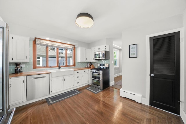 kitchen featuring stainless steel appliances, a baseboard radiator, a sink, and backsplash