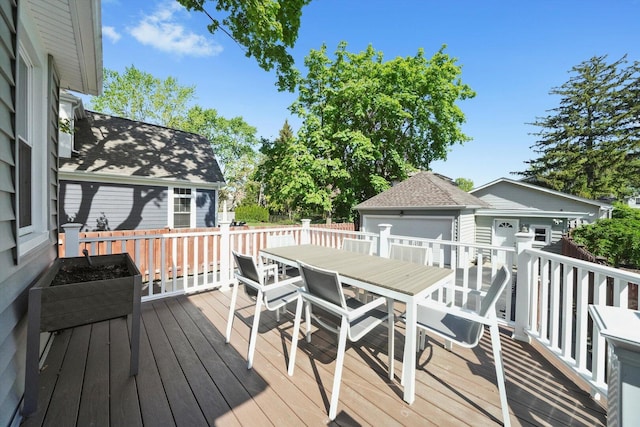 wooden deck with an outbuilding, outdoor dining area, and a detached garage