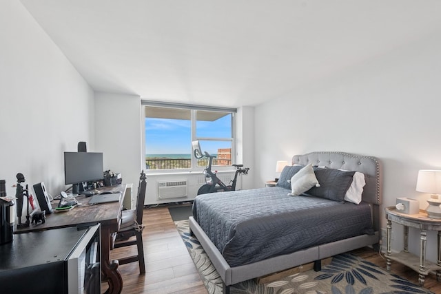 bedroom with wood finished floors, a desk, and a wall unit AC