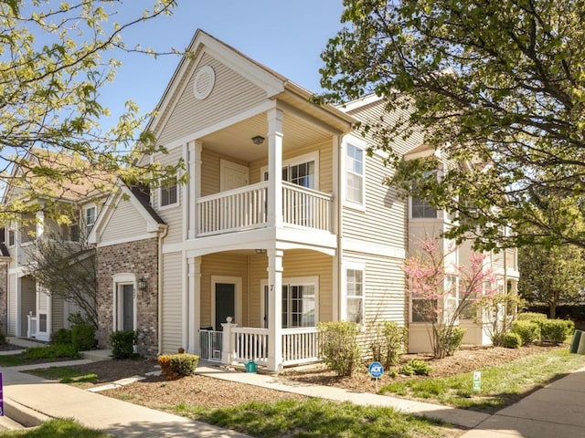 view of front of property featuring a balcony, a porch, and brick siding