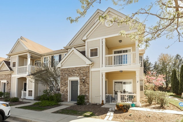 multi unit property with a balcony and brick siding