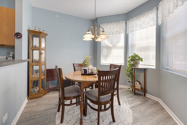 dining area featuring light wood-style floors, a chandelier, healthy amount of natural light, and baseboards