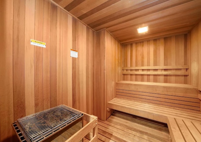 sauna with wooden walls, wooden ceiling, and wood-type flooring