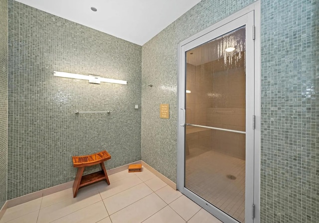 full bath with tile patterned flooring, tile walls, and a shower stall