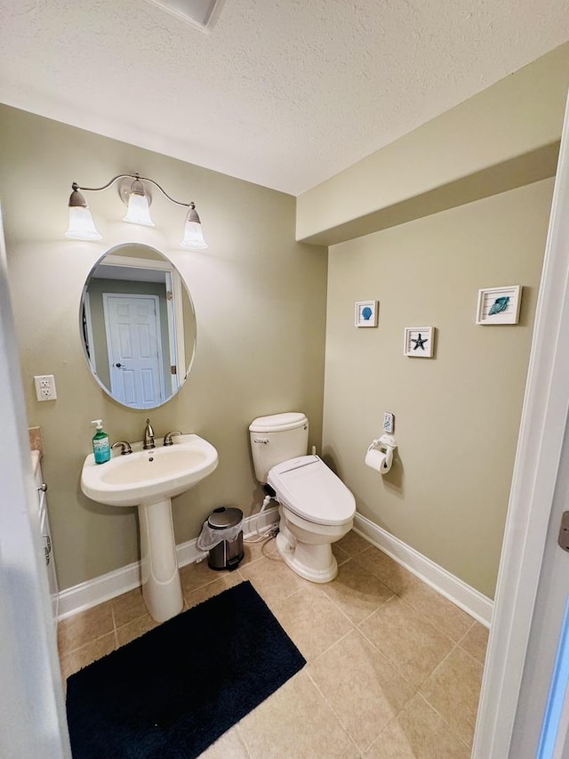 bathroom with tile patterned floors, toilet, a textured ceiling, and baseboards