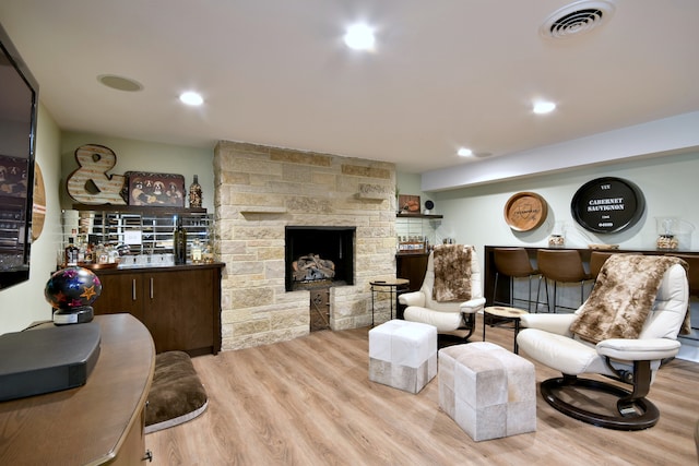 living room featuring a dry bar, wood finished floors, a fireplace, and recessed lighting