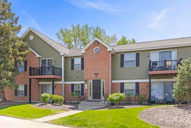 townhome / multi-family property with brick siding, a front lawn, and a chimney