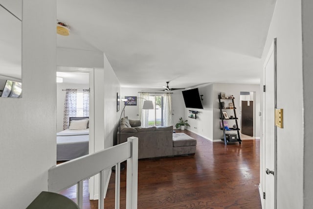 living area with ceiling fan, plenty of natural light, and dark wood-style flooring