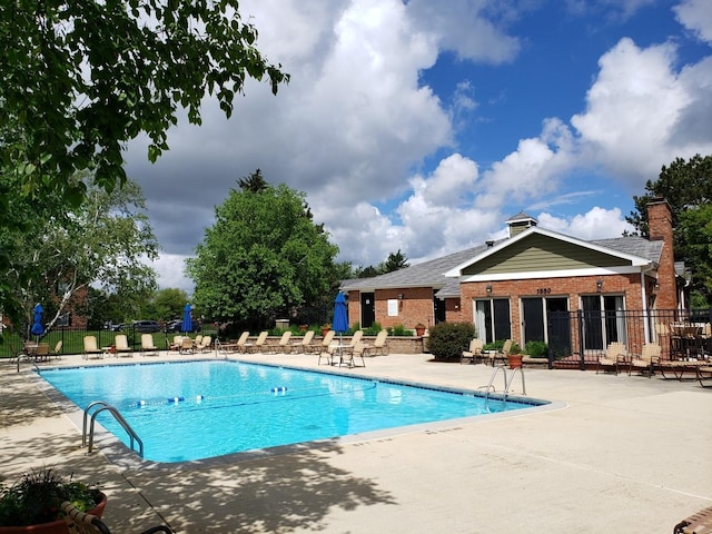 community pool with fence and a patio area