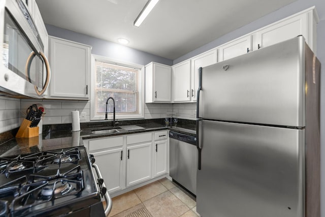 kitchen featuring stainless steel appliances, a sink, white cabinetry, backsplash, and light tile patterned floors