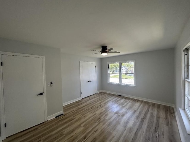 spare room featuring wood finished floors, a ceiling fan, and baseboards
