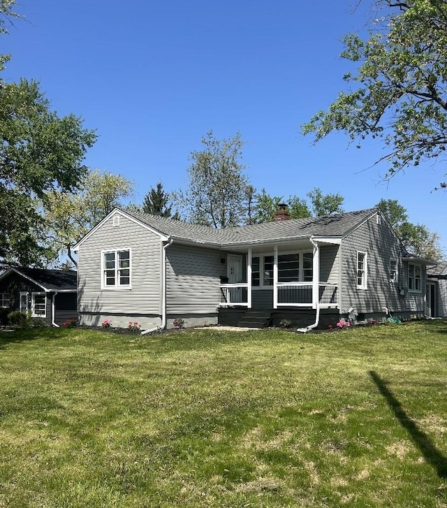 back of property featuring a porch, a chimney, and a yard