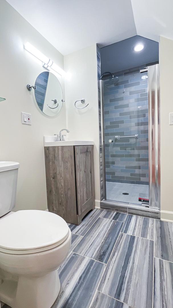 full bath with a stall shower, toilet, vanity, wood finish floors, and recessed lighting