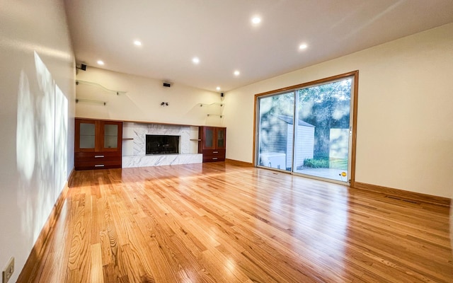 unfurnished living room with light wood-style flooring, a premium fireplace, and recessed lighting
