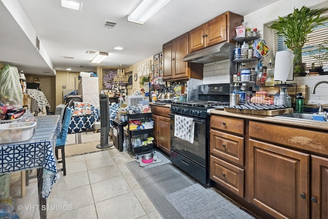 5814 N Campbell Ave, Chicago, IL 60659 - kitchen with black gas stove, under cabinet range hood, light tile patterned flooring, decorative backsplash, and brown cabinetry