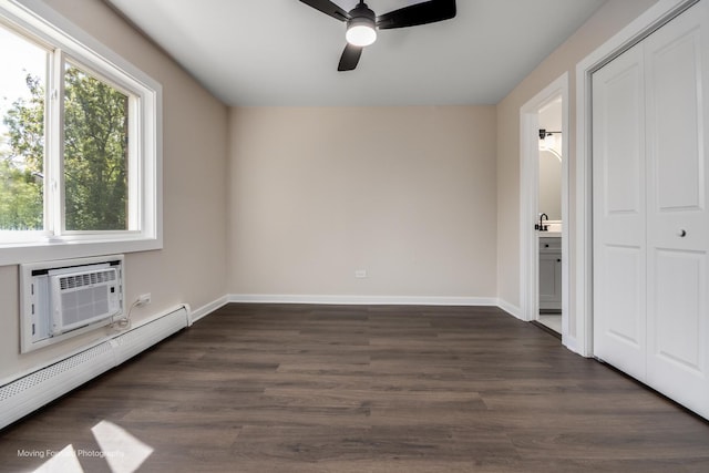 unfurnished bedroom with a baseboard heating unit, baseboards, a closet, dark wood-style floors, and ensuite bath