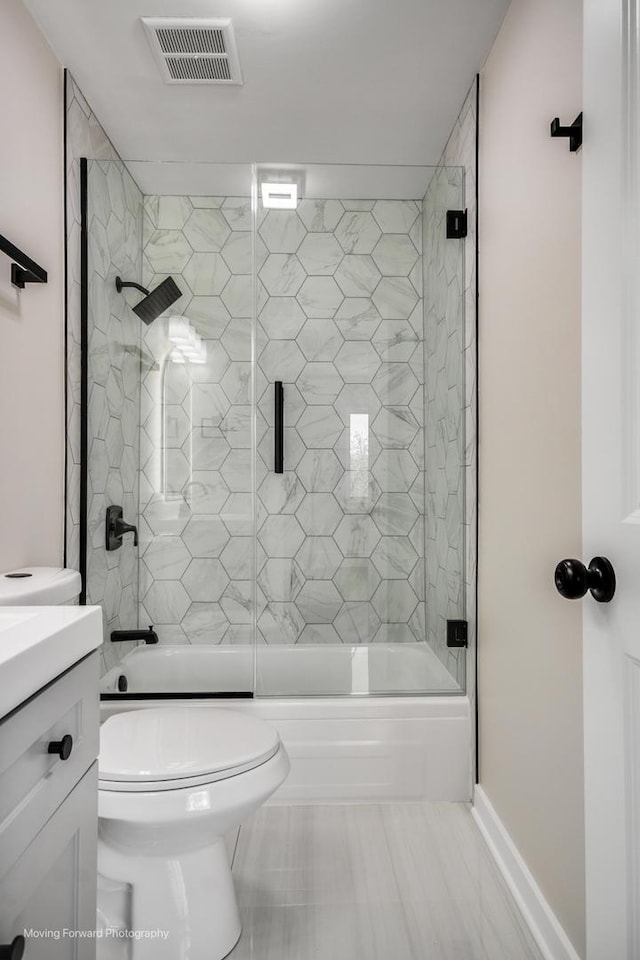 bathroom with bath / shower combo with glass door, vanity, and toilet