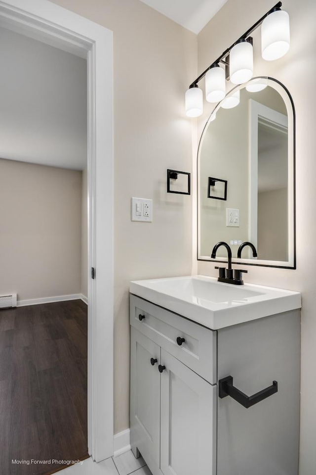 bathroom featuring baseboards, wood finished floors, vanity, and a baseboard radiator