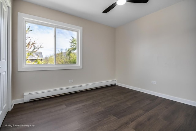 spare room featuring a baseboard radiator, a ceiling fan, dark wood finished floors, and baseboards